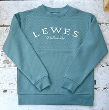 Load image into Gallery viewer, Green quilted crew neck sweatshirt featuring "Lewes Delaware" in white text, laid flat on a distressed white wooden surface.