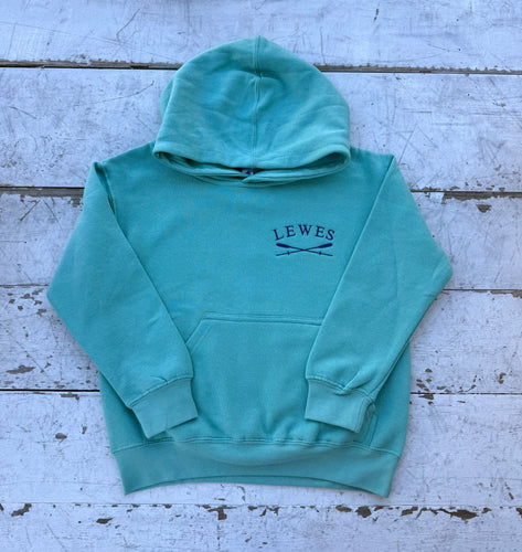 Front view of a vibrant green children's pullover hoodie with an embroidered 'LEWES' logo and crossed oars on the chest, featuring a kangaroo pocket and hood, laid on a distressed white wooden surface.