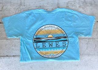 Caribbean t-shirt with a circular back graphic featuring a golden sunset over blue water, text 'Lewes Delaware Est. 1631 Outdoor Adventure' and 'Weekends, Weekdays, Whenever', with crossed paddles.