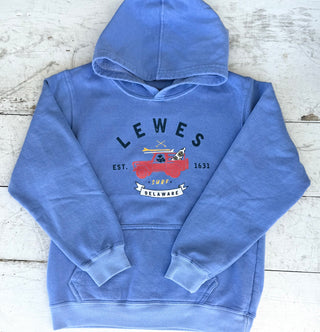washed perywinkle vintage wash hoodie with a red pickup truck and surfboards graphic, text "Lewes Delaware Est. 1631 Surf", laid flat on a distressed white wooden background.